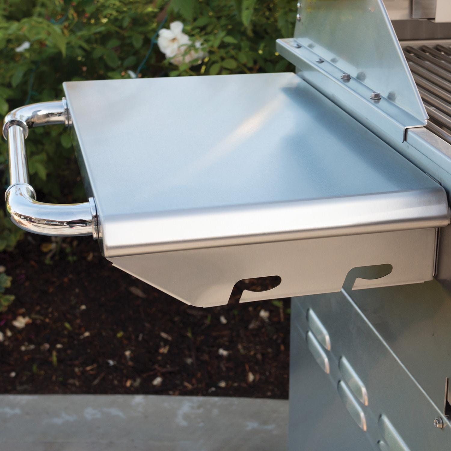 Metallic grill lid with handle on a grill against a natural background