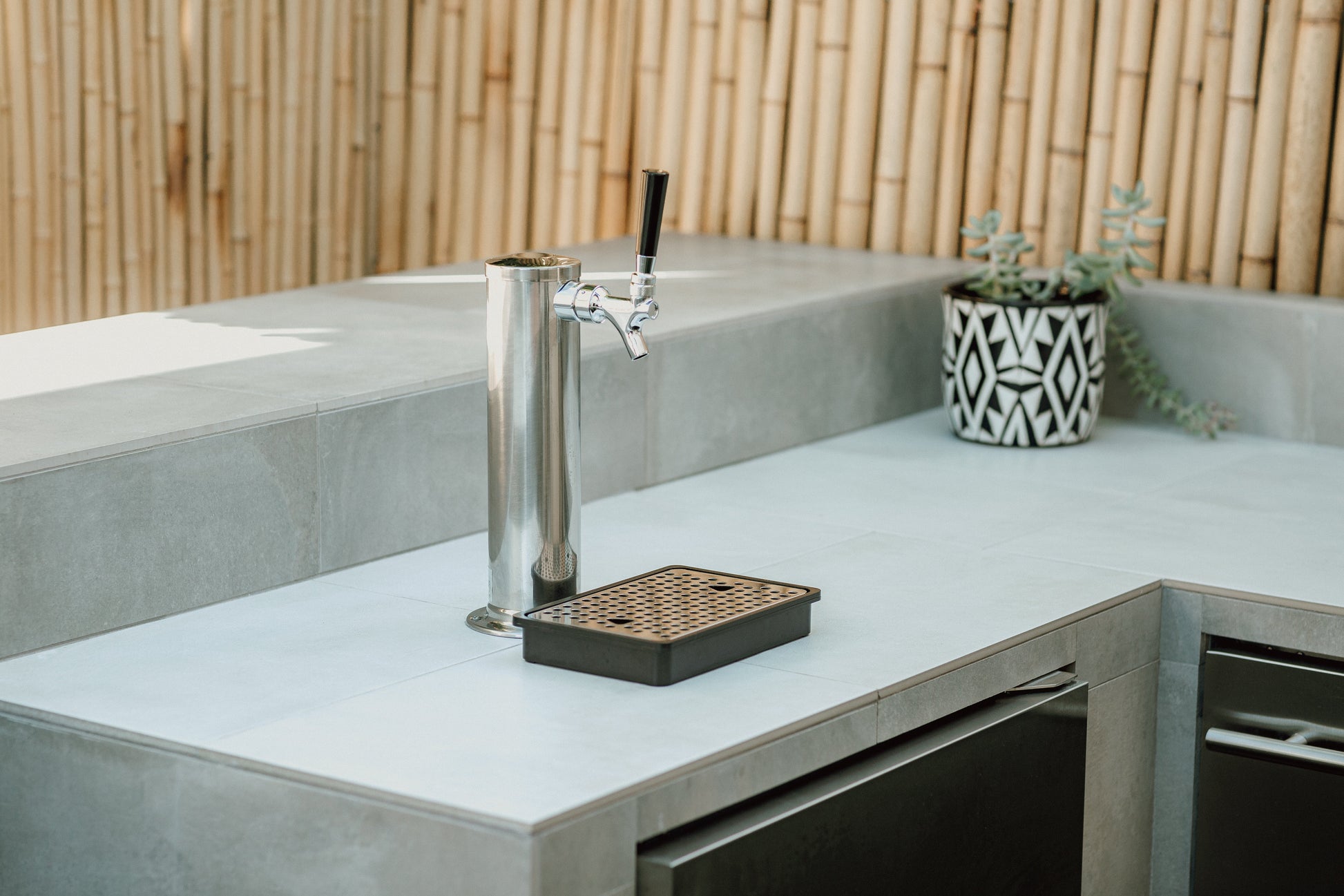 Metal beer tap on a concrete surface with a bamboo background