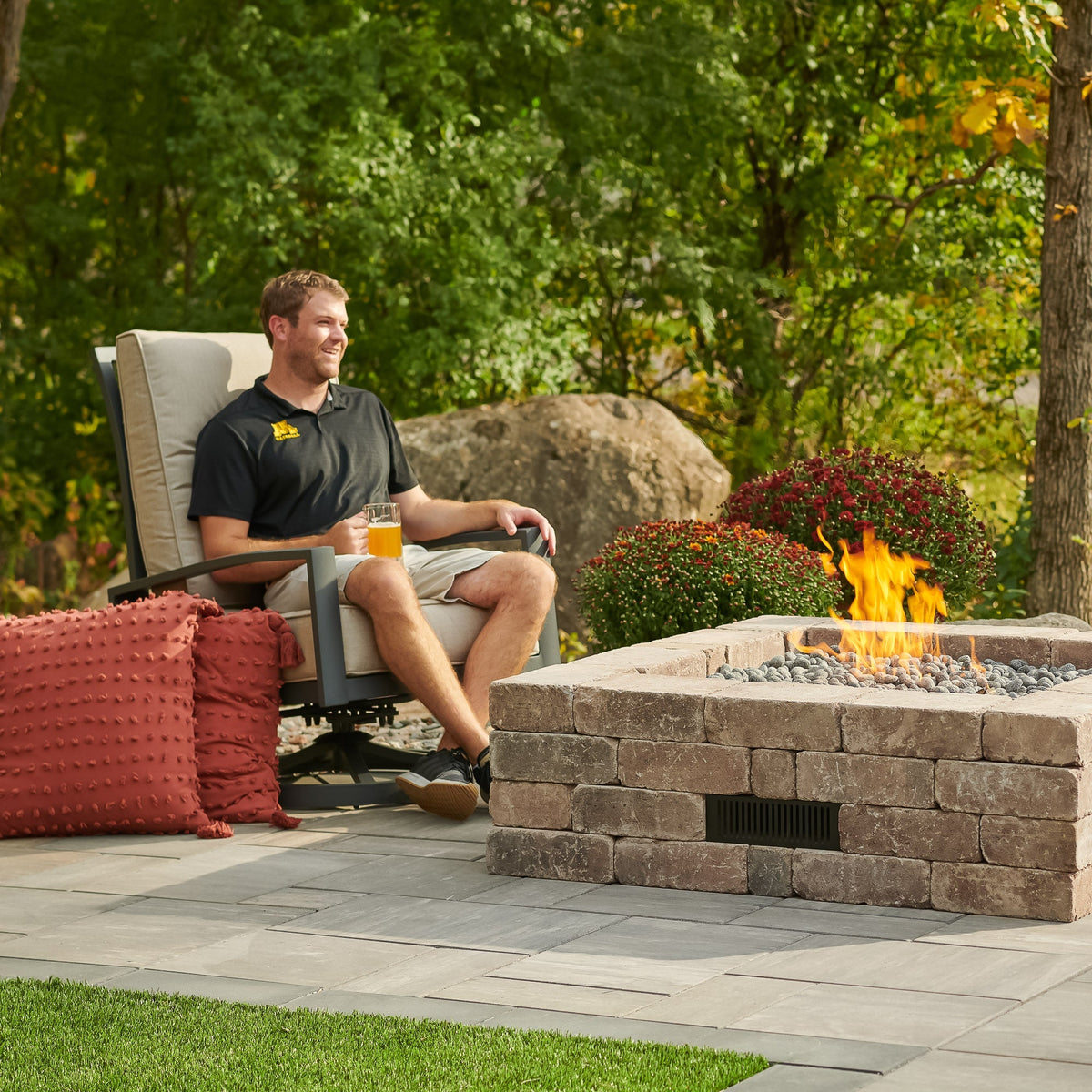 Person sitting next to the Bronson Block Square Gas Fire Pit Kit