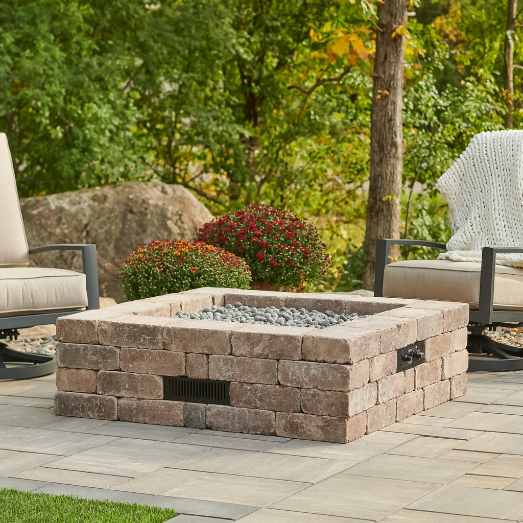 Bronson Block Square Gas Fire Pit Kit with lava rock in an outdoor space