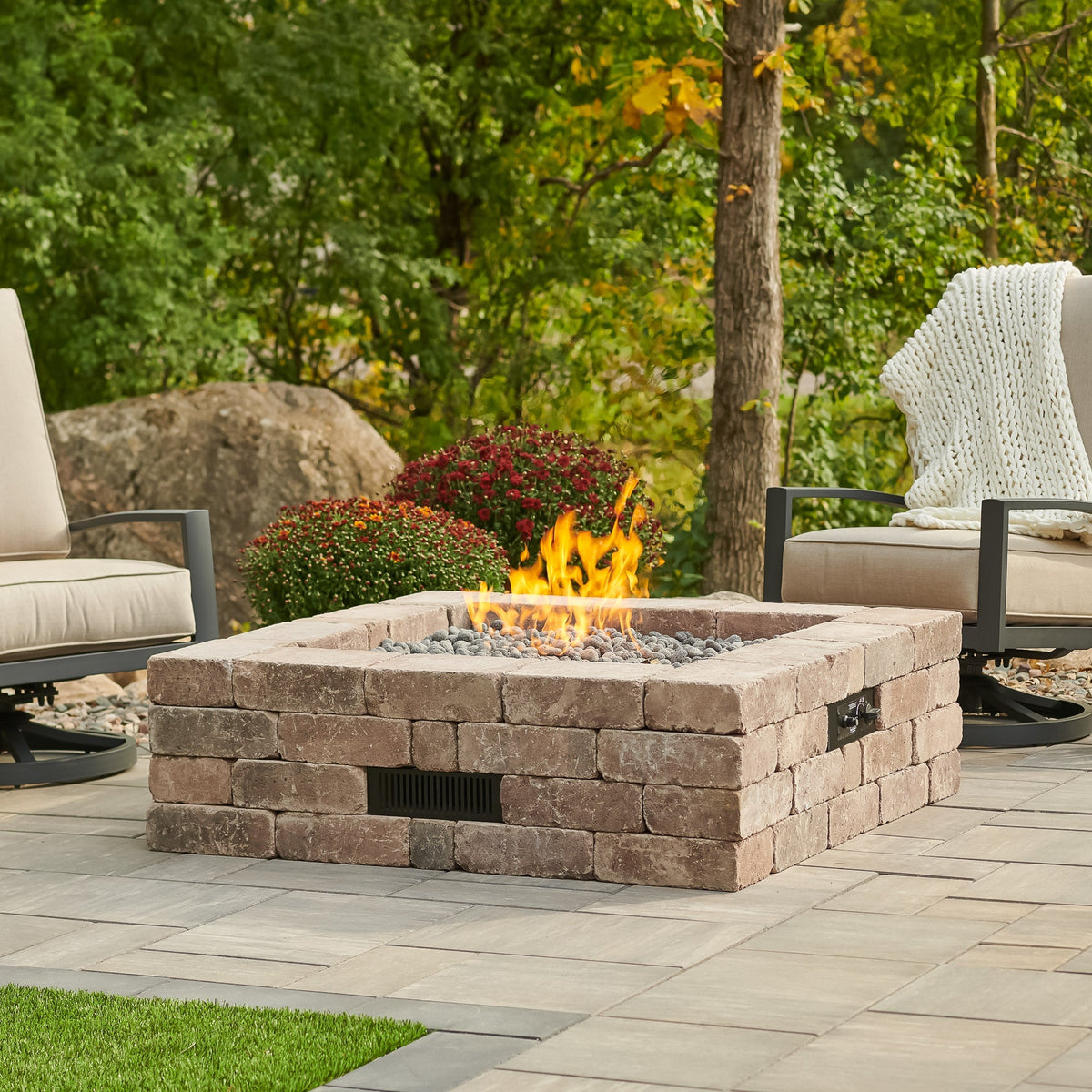 Bronson Block Square Gas Fire Pit Kit on a patio with patio furniture