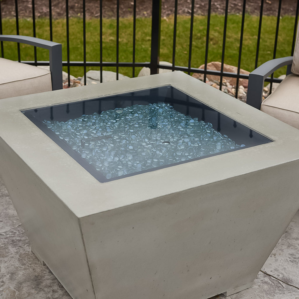 Close view of the burner, glass cover and fire media on a Cove Concrete Trapezoid 37-inch gas fire pit bowl