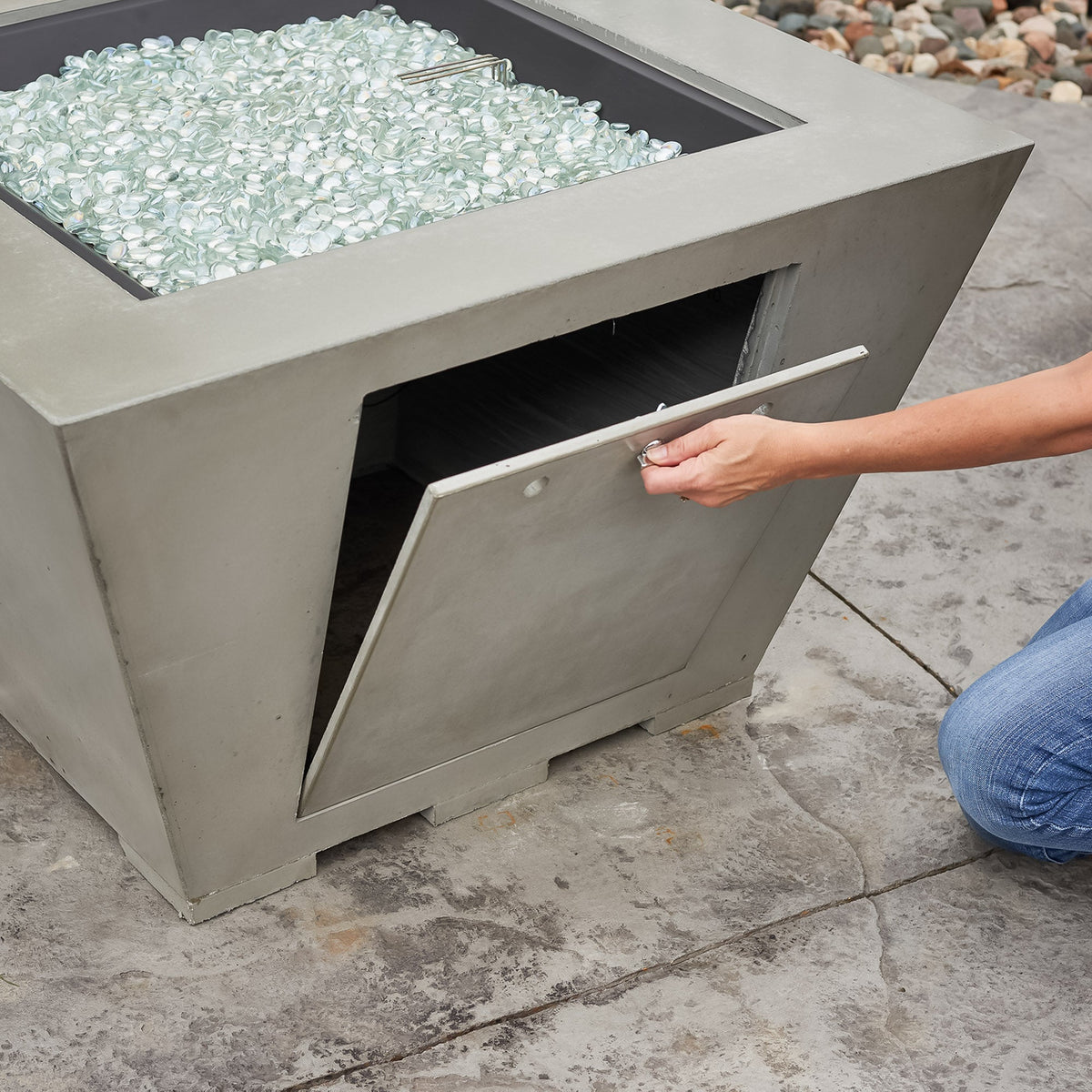 Person opening the side access door on a Cove Concrete Trapezoid 37-inch gas fire pit bowl