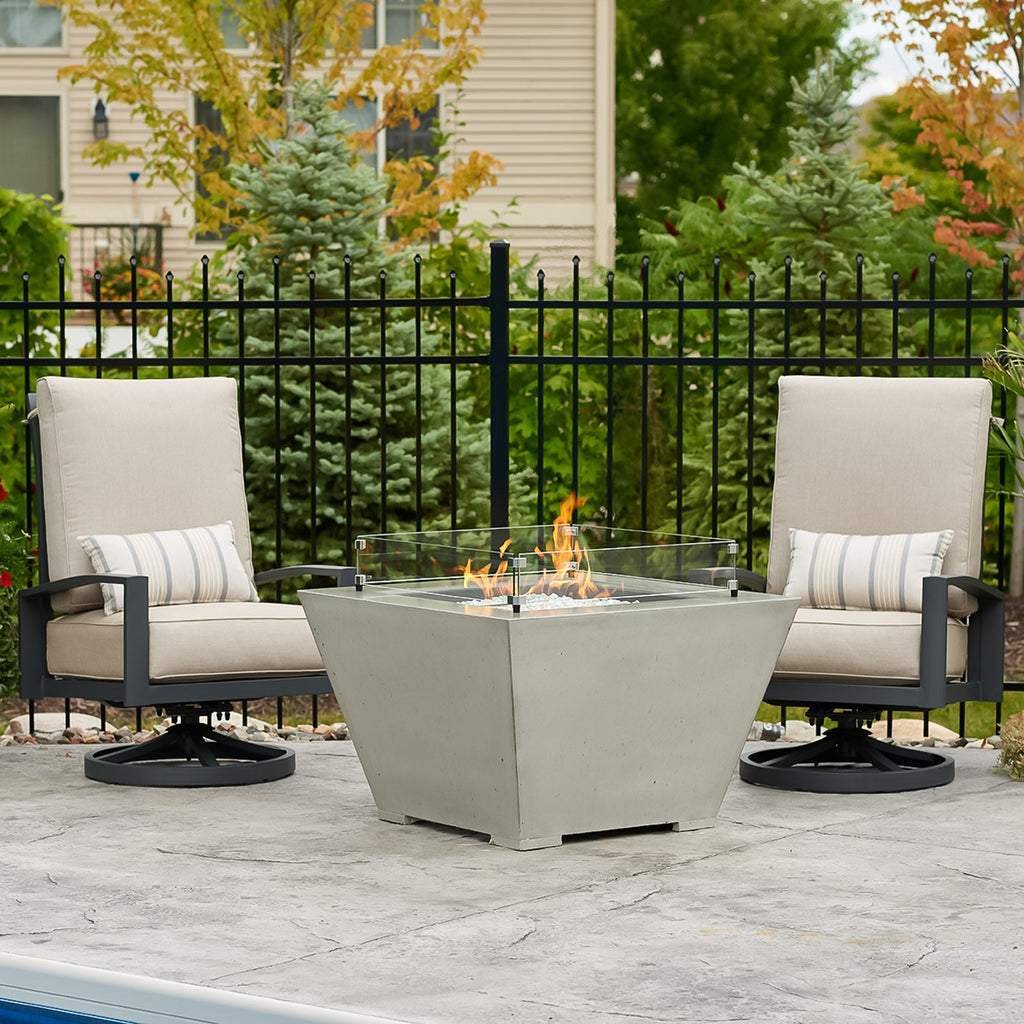 Natural Grey Cove Concrete Trapezoid 37-inch gas fire pit bowl with a glass wind guard protecting a large flame