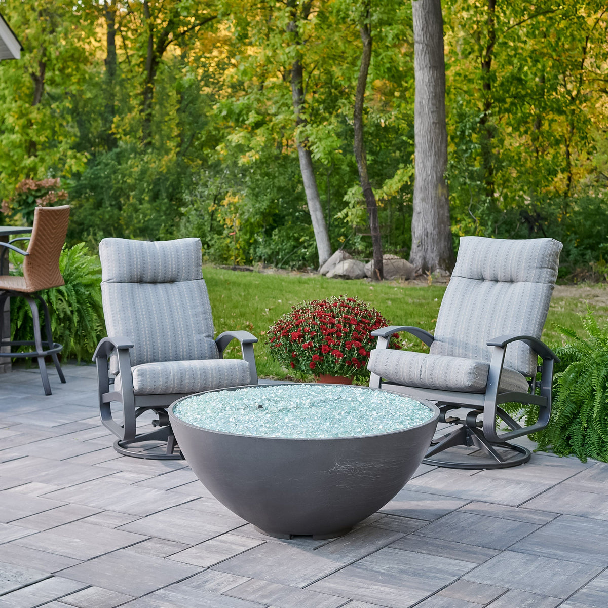 Midnight Mist Cove Concrete Edge 42-inch gas fire pit bowl unlit next to lounge chairs and flowers